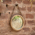 Round mirror with wooden frame and rope hanger.