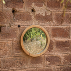 A round wooden-framed mirror mounted on a wall