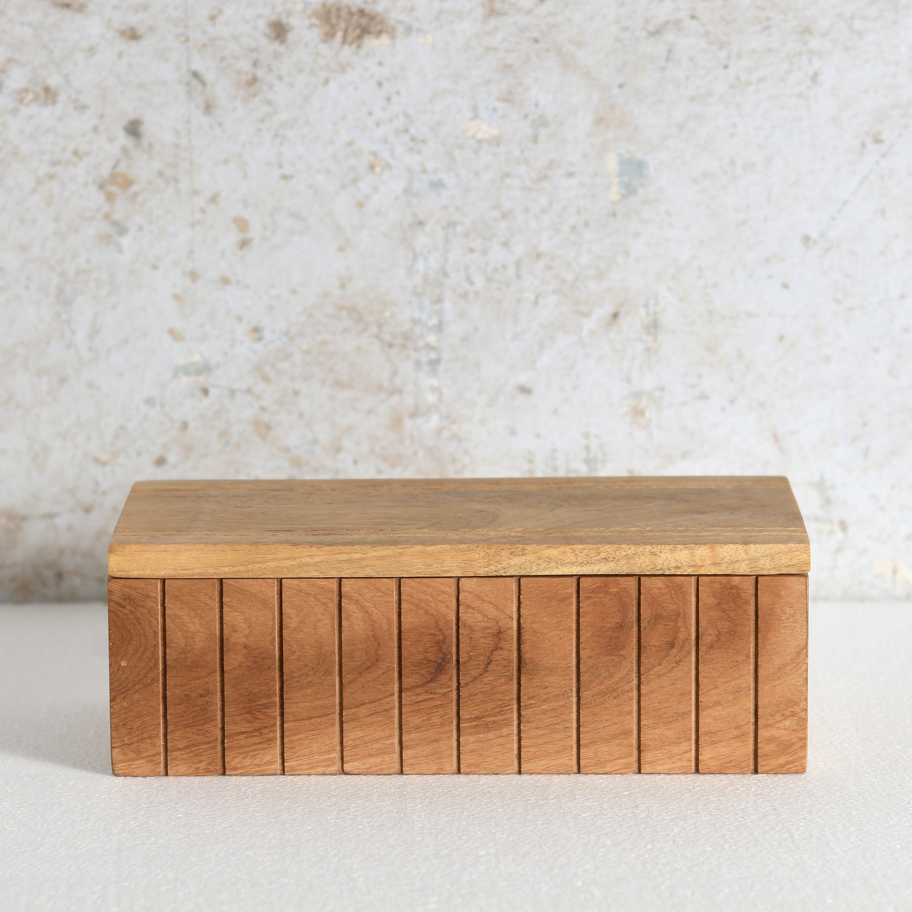 A rectangular wooden box with a slatted front and a flat lid.