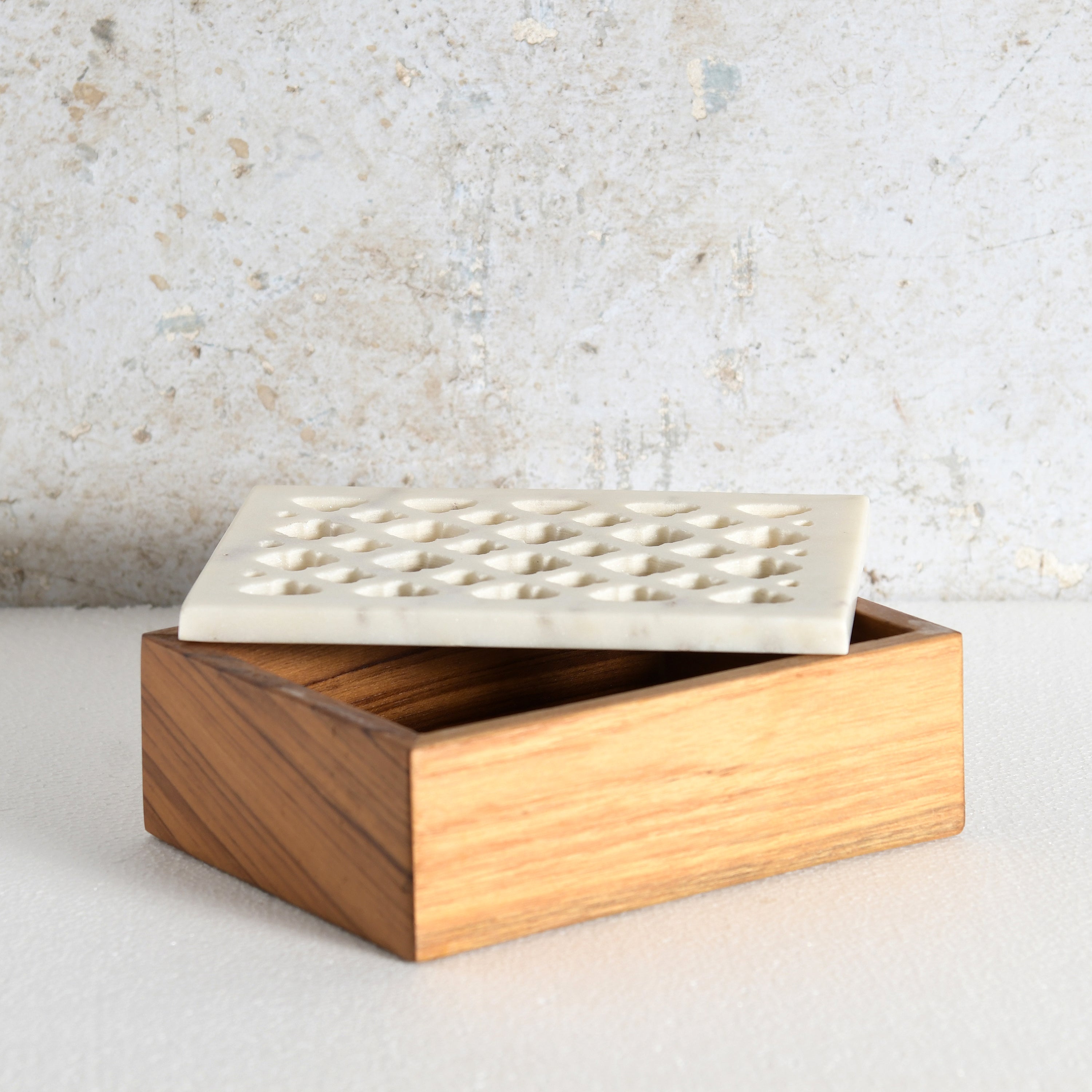 A rectangular wooden box crafted from sheesham wood, featuring a white marble lid with a grid of small geometric cutouts.