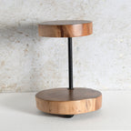 A modern two-tier wooden platter stand featuring circular wood slices at the top and bottom tiers connected by a slim black metal pole.