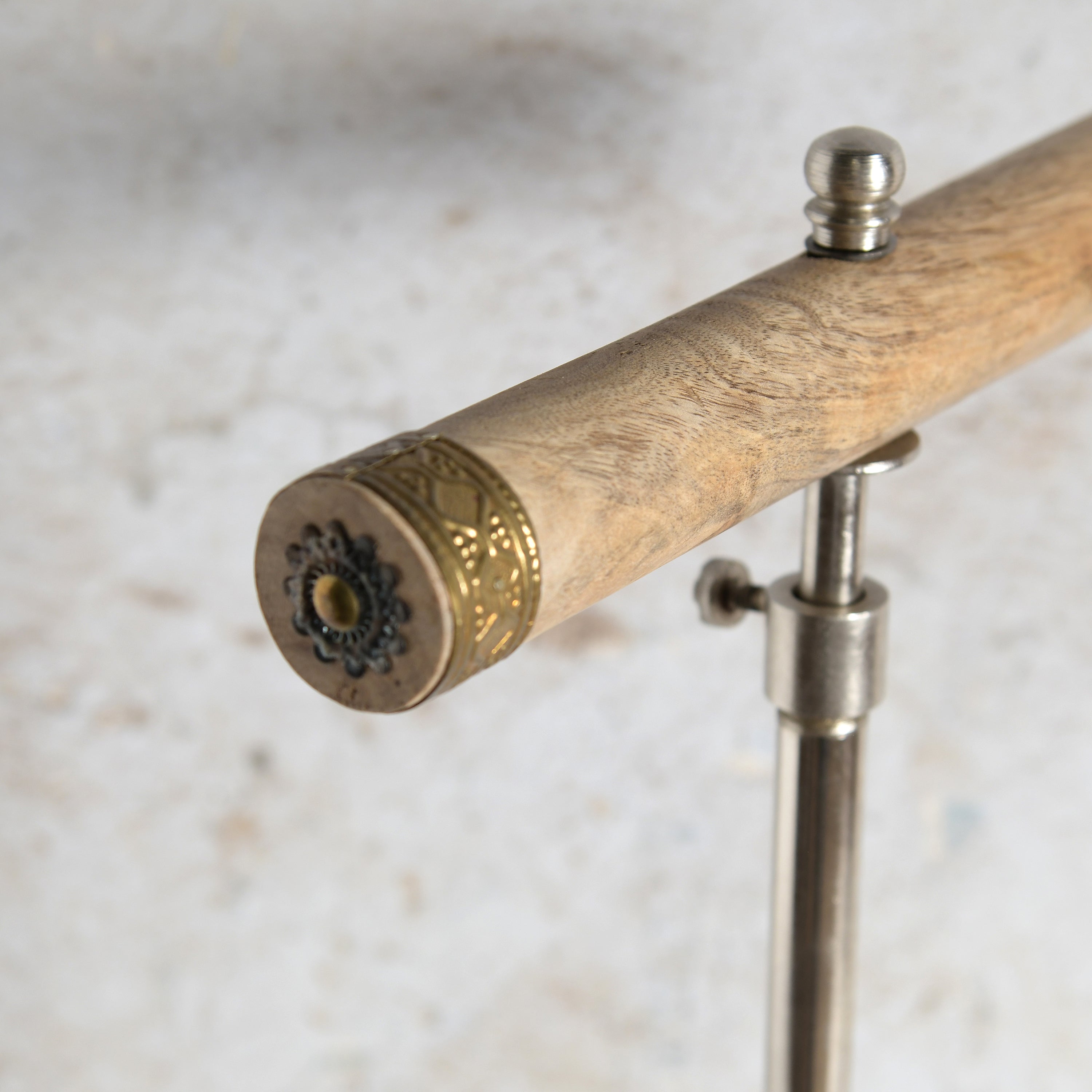Close-up of a wooden Jewelry stand handle with ornate gold-toned metal detailing and a silver metal.