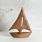 A minimalist wooden sailboat sculpture with a warm medium-brown finish, perfect for living room shelf.