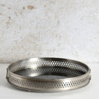 A round metal mirror tray with side handles for decorative use.