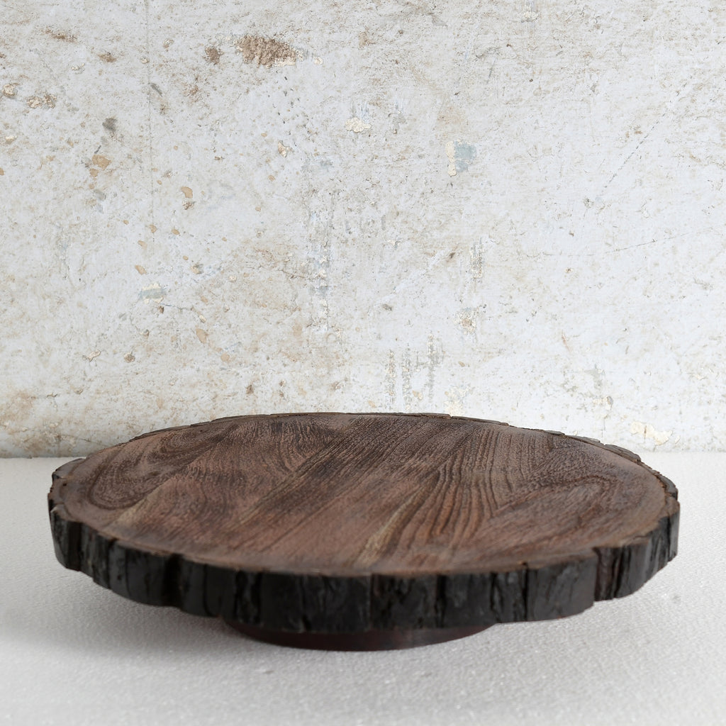 A round dark brown wooden serving board or tray | Lazy Susan with a natural bark edge.