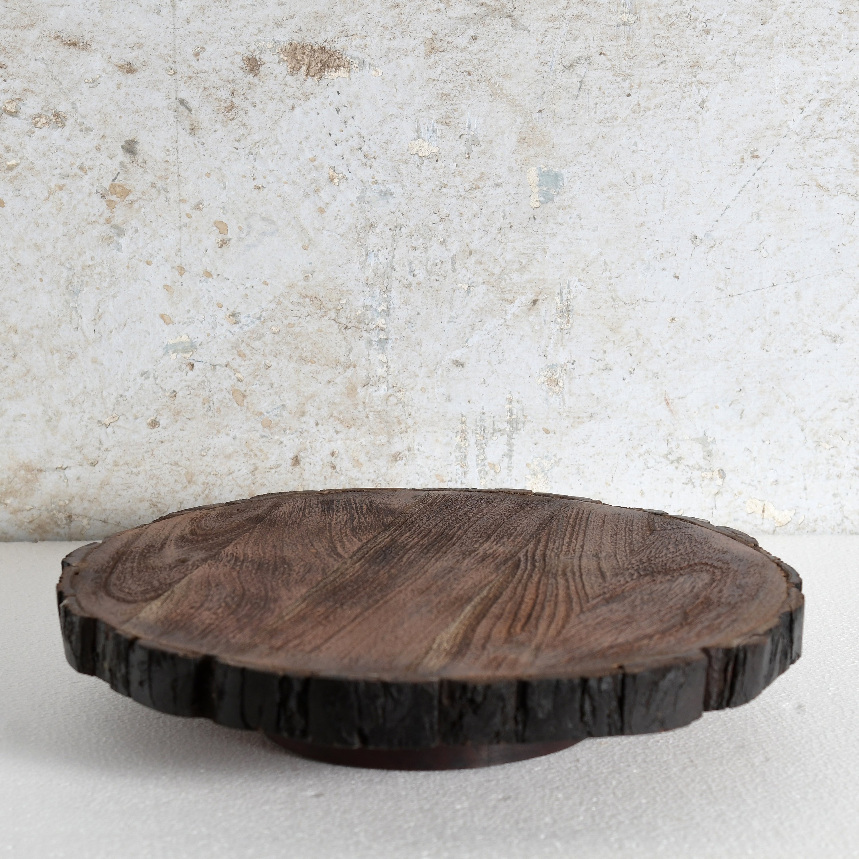 A round dark brown wooden serving board or tray | Lazy Susan with a natural bark edge.