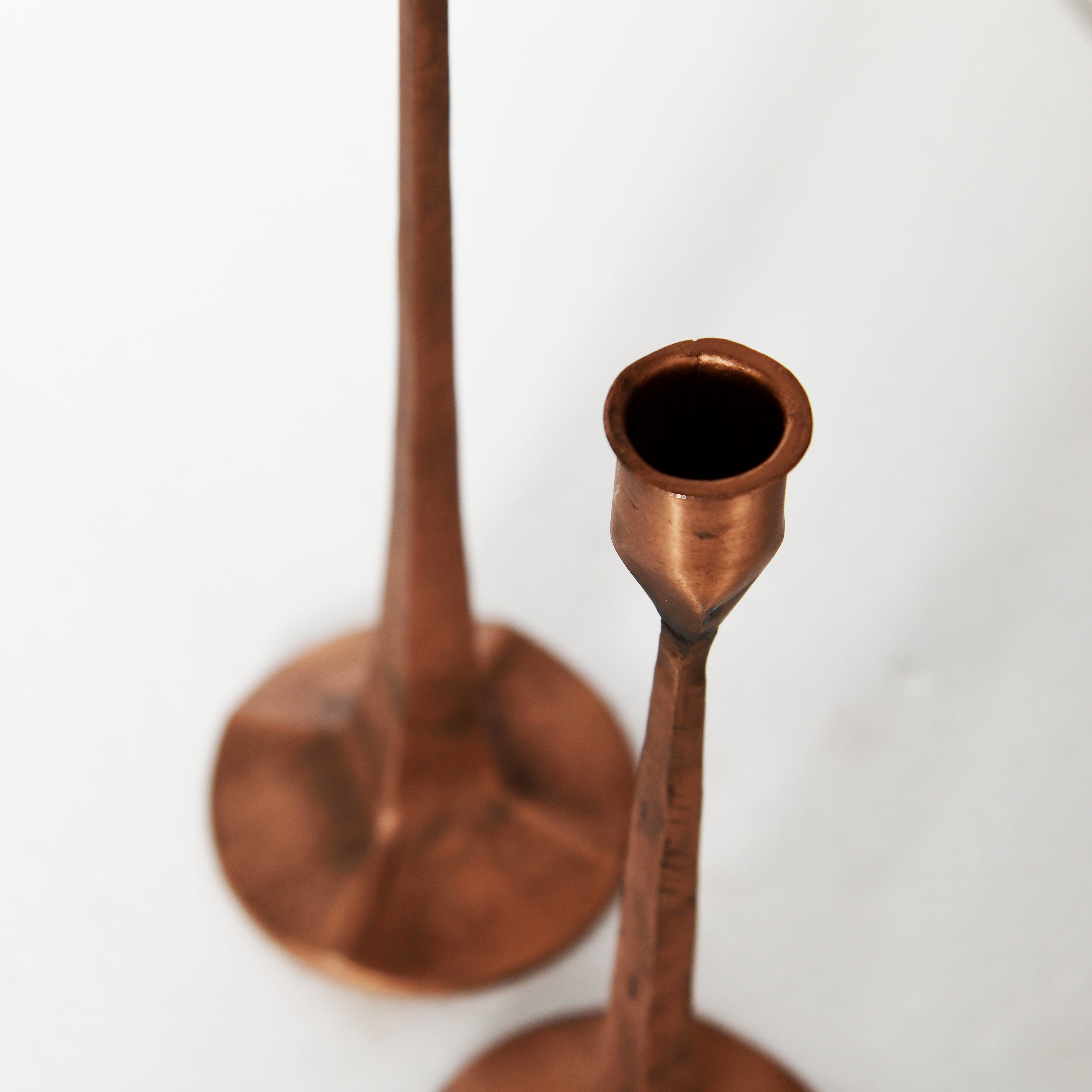 Two hammered copper candlesticks with a warm metallic finish, shown on a clean white background.