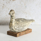 A distressed clay duck decor with a textured, weathered finish, mounted on a rustic rectangular wooden base.