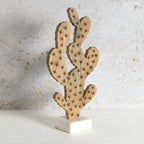 Decorative wooden cactus sculpture with visible star-shaped prickles, mounted on a white rectangular base,.