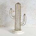 A cactus-shaped metal wire candle holder with a round white marble base.
