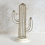 A cactus-shaped metal wire candle holder with a round white marble base.