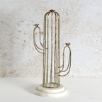 A cactus-shaped metal candle holder with a vertical wire cage body, two curved arms, small bird finials at the tips, and a round white marble base.