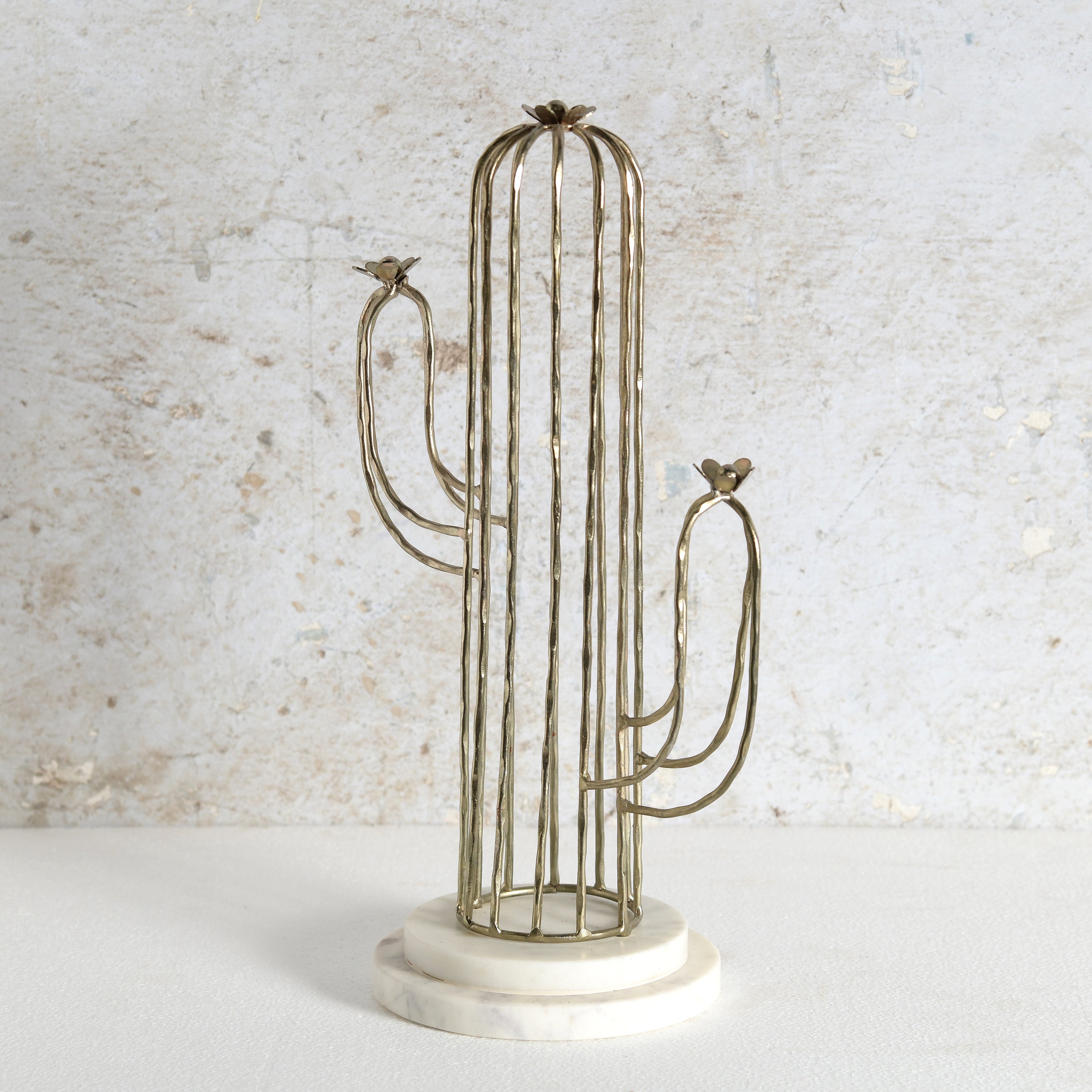 A cactus-shaped metal candle holder with a vertical wire cage body, two curved arms, small bird finials at the tips, and a round white marble base.