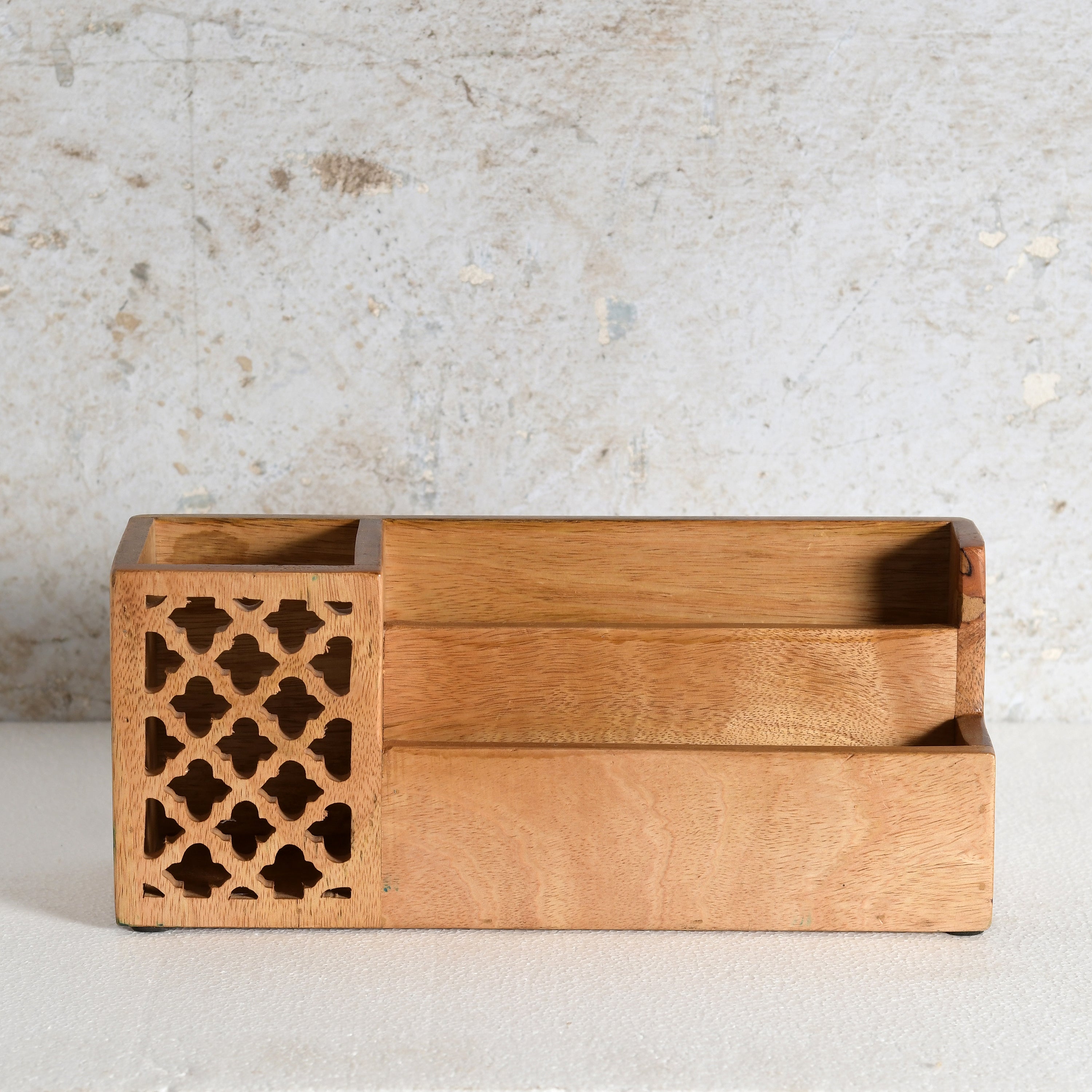 A rectangular wooden desk organizer with a warm honey-toned finish, featuring a decorative lattice cutout panel on the left side and three open storage compartments.