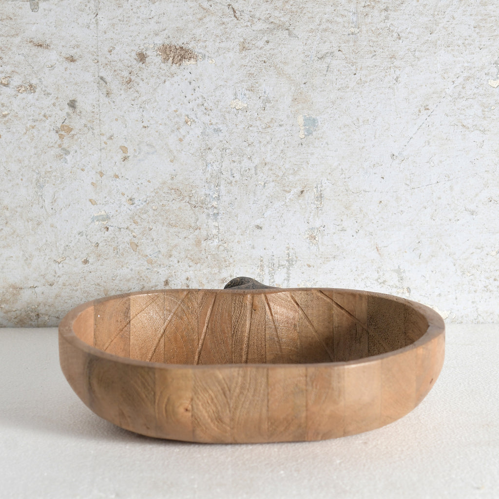 A round wooden apple shaped bowl with a small handle.