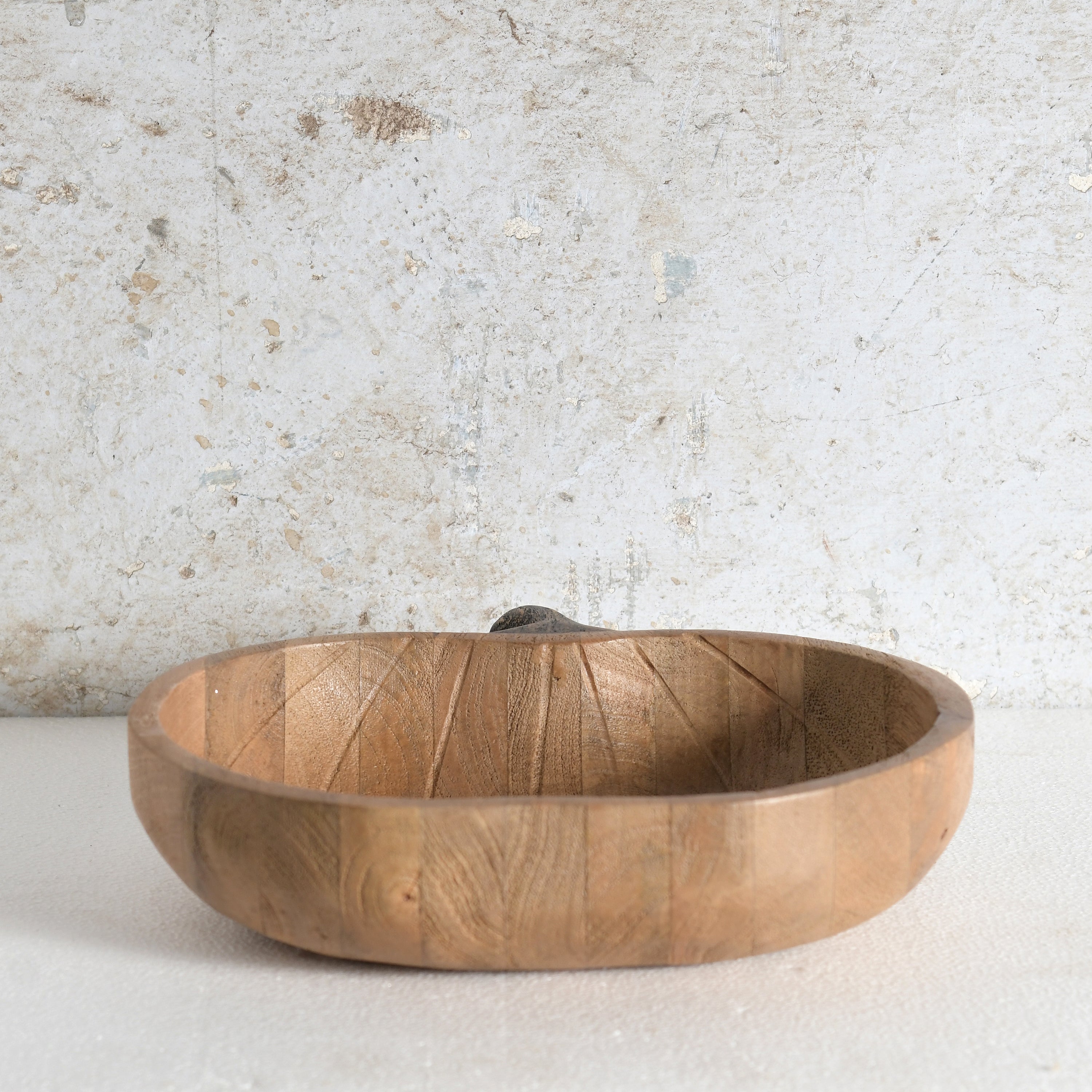A round wooden apple shaped bowl with a small handle.