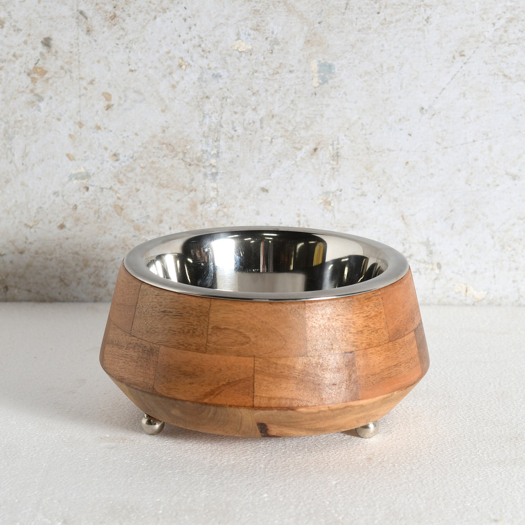 A pet feeder with a warm brown wood-grain outer body and a shiny silver stainless steel interior, resting on small silver feet.