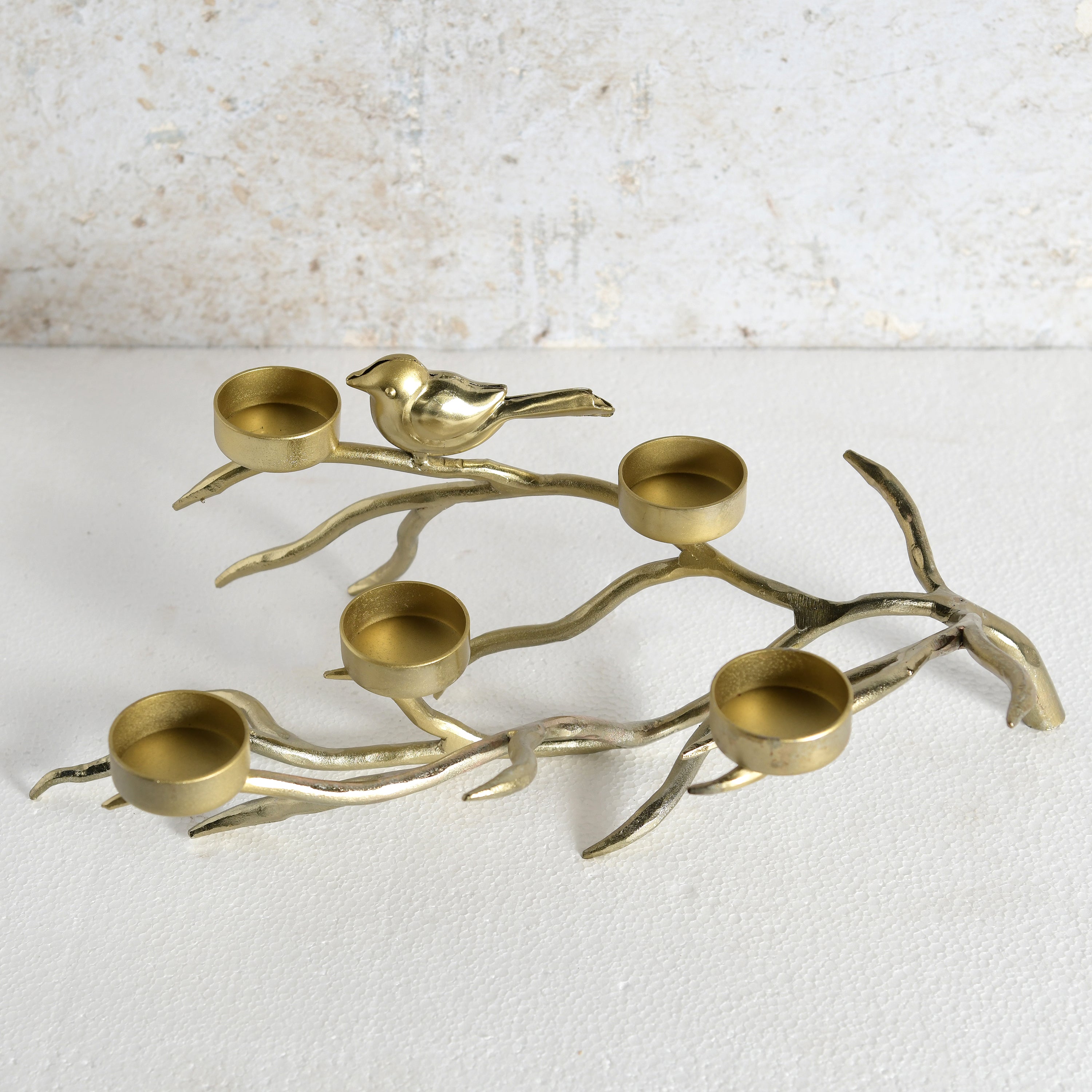 A brass bird and branch candle holder with five candle cups.