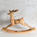 A handcrafted wooden rocking deer toy with gold-painted accents on the antlers, hooves, and side details.