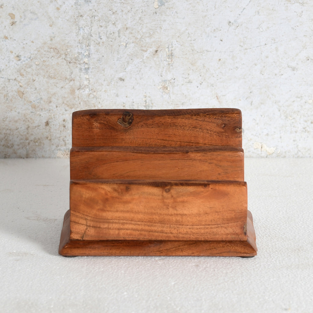 A small three-tier wooden napkin holder made of warm medium-brown wood with visible grain and knots.