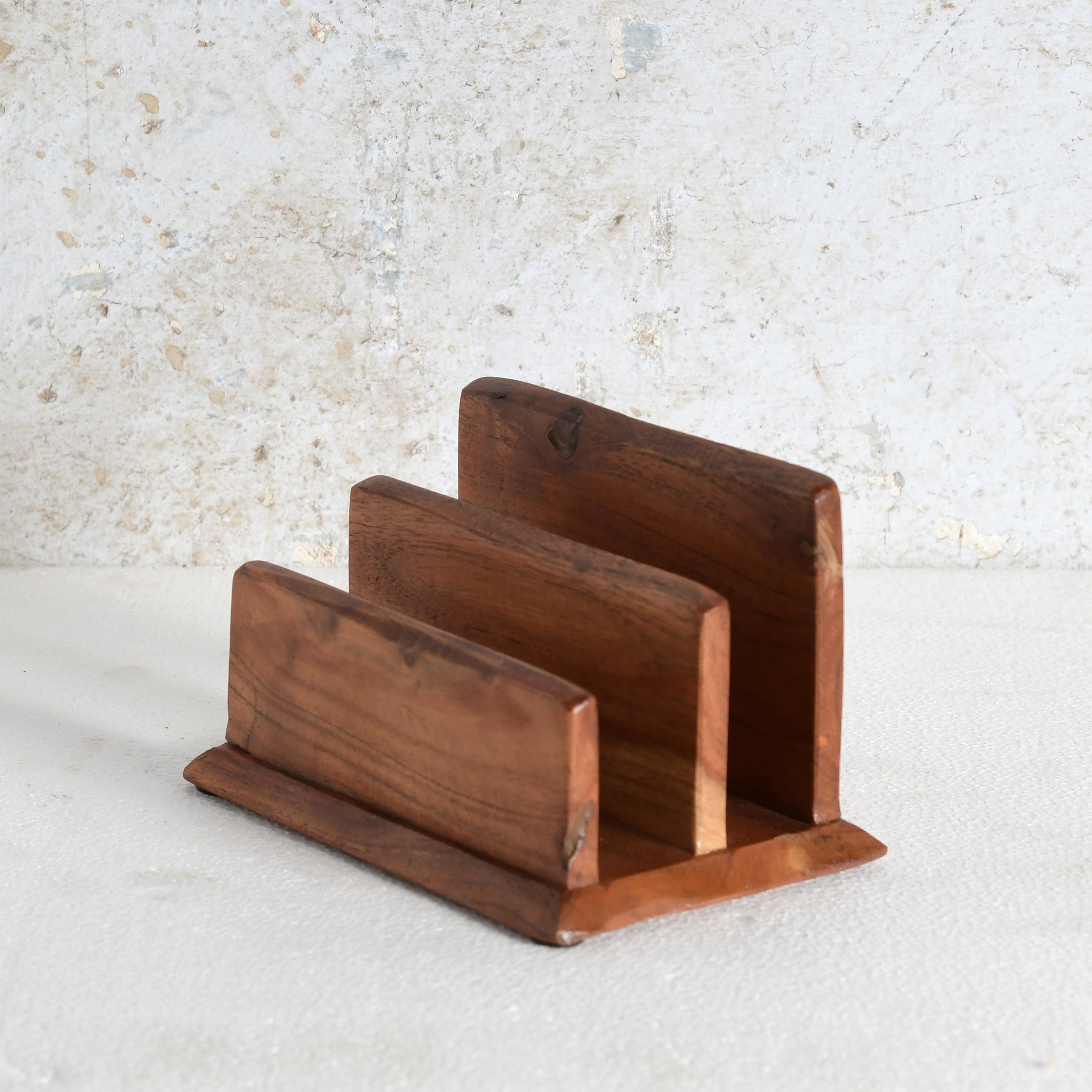 A three-tier wooden napkin holder with a warm medium-brown finish and visible wood grain.