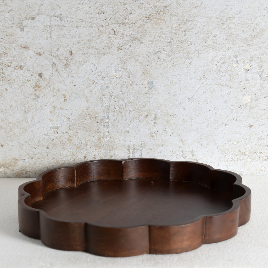 A scalloped-edge wooden serving tray in a dark brown finish.