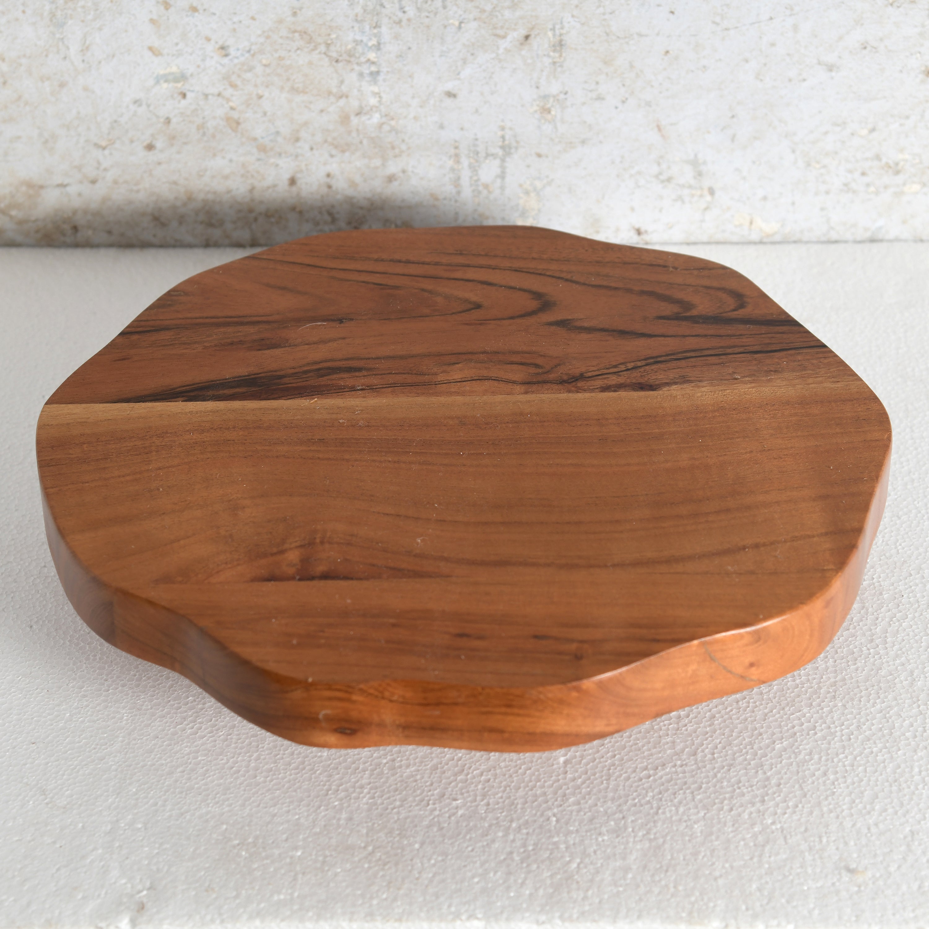 An octagonal wooden serving board | Lazy Susan with a natural wavy edge and prominent dark grain patterns.