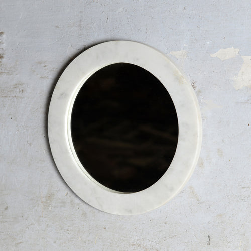 A round white marble wall mirror with a thick, textured border.