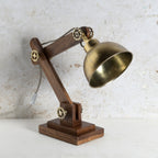 A steampunk-style adjustable desk lamp with a dark brown wooden articulated arm, brass metal base and shade, and decorative brass wheel accents.