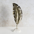 Decorative iron feather structure with brass finish and white marble base.