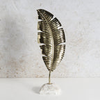 Decorative iron feather structure with brass finish and white marble base.