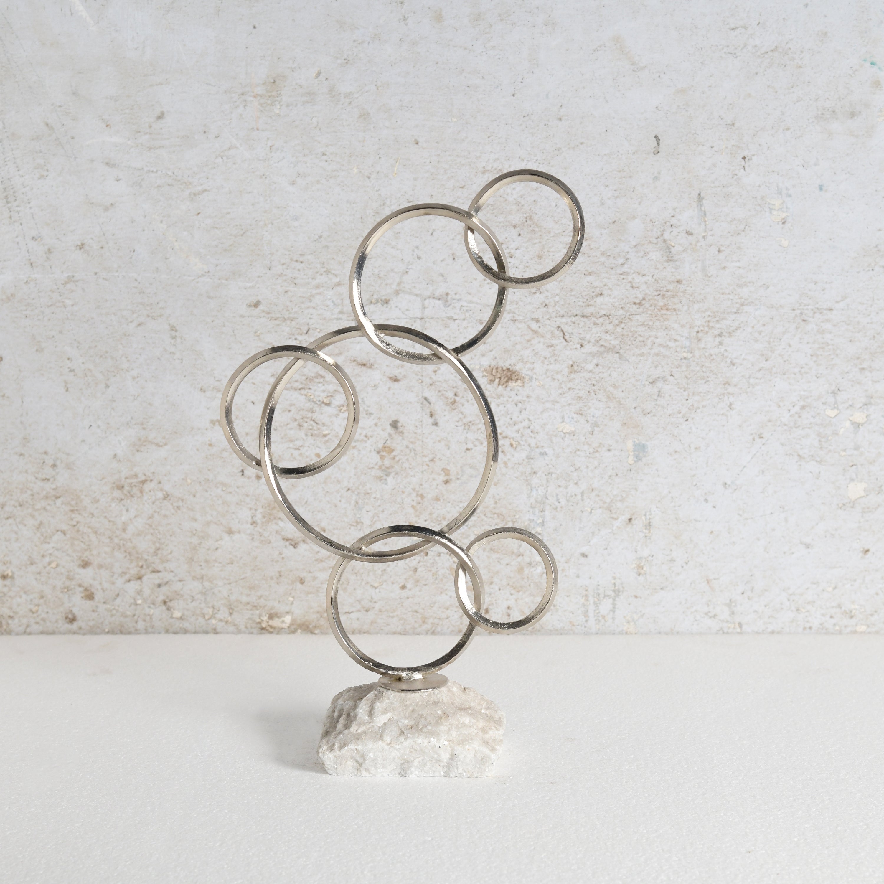 Rings structure iron decor piece with white marble base.