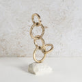 Gold finish, structured rings iron decor piece with marble base.