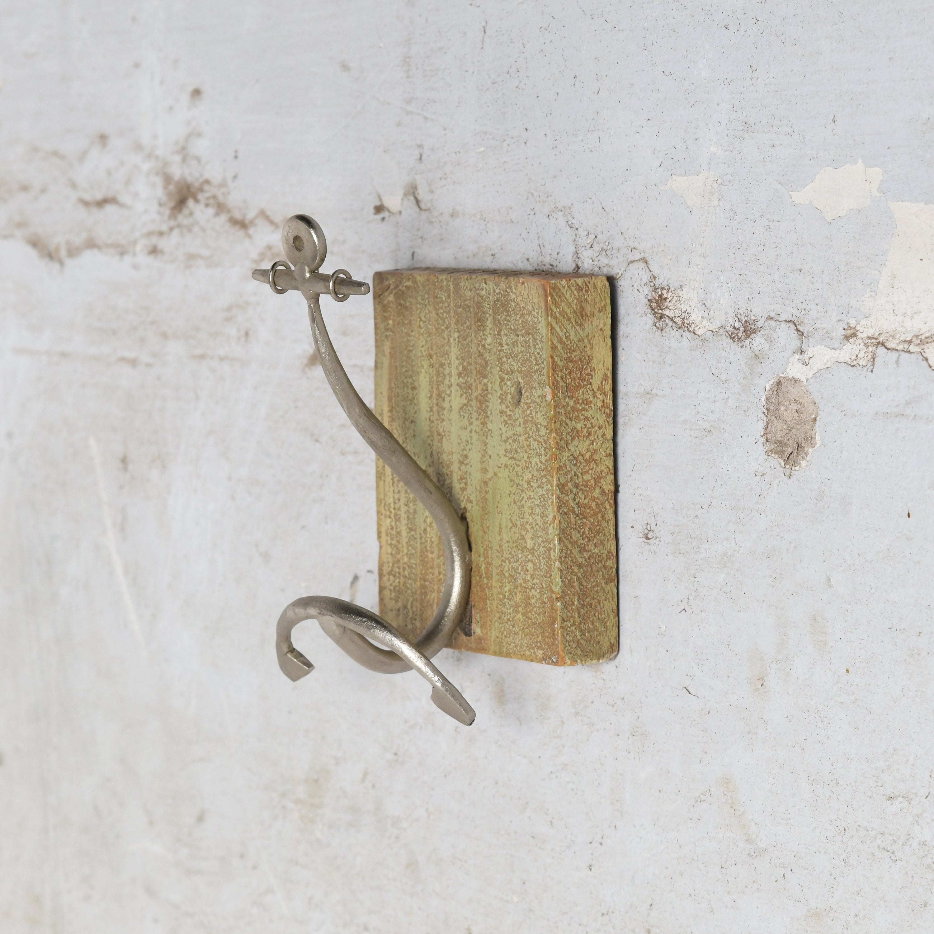 Metal anchor shaped hook mounted on wooden frame